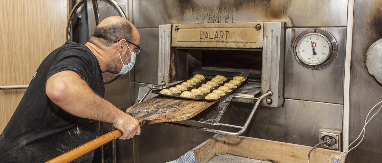 Un profesional de la panadería introduce en el horno una bandeja con productos elaborados de manera artesanal