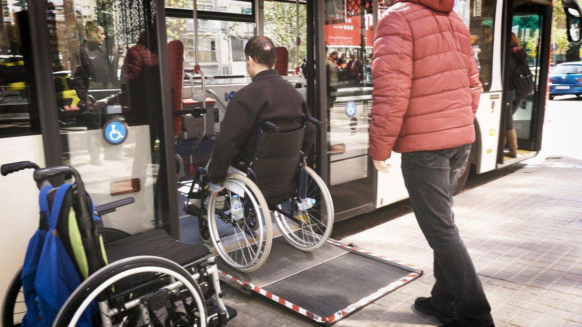 Un voluntario de la Fundació TMB ayuda a una persona en silla de ruedas, el verano pasado