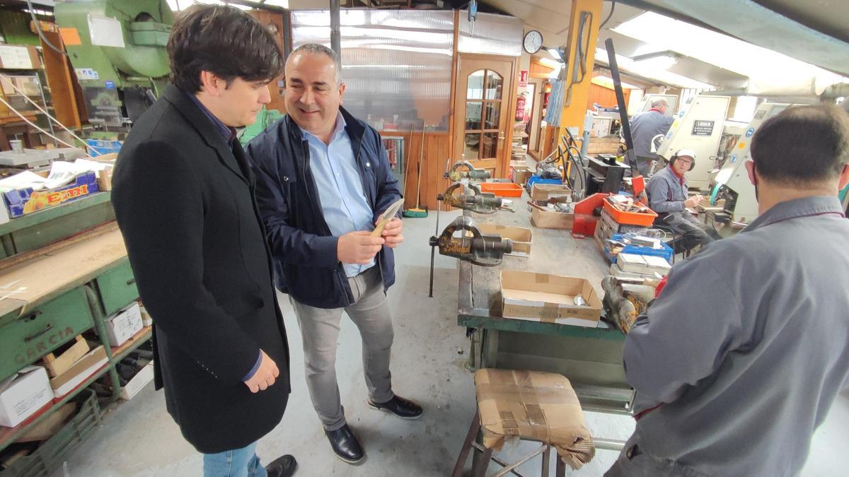 El Alcalde taramundés, César Villabrille, muestra un cuchillo a Borja Sánchez durante la visita a las instalaciones de La Cuchillería.