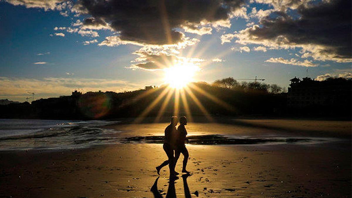 Dos personas pasean por una playa.