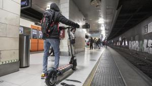 Un pasajero con un patinete eléctrico en la estación de Rodalies de plaza Catalunya, en Barcelona.