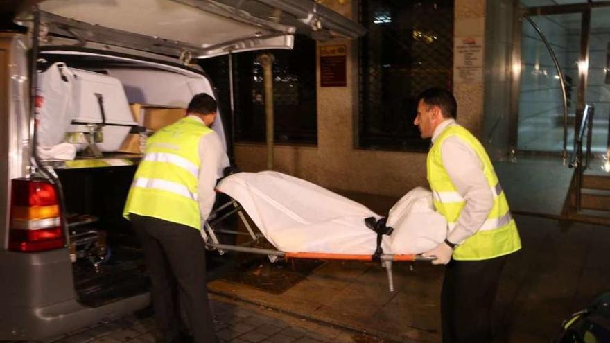 Los trabajadores de la funeraria trasladan el cadáver de la víctima del crimen de la calle Zamora. // Nick