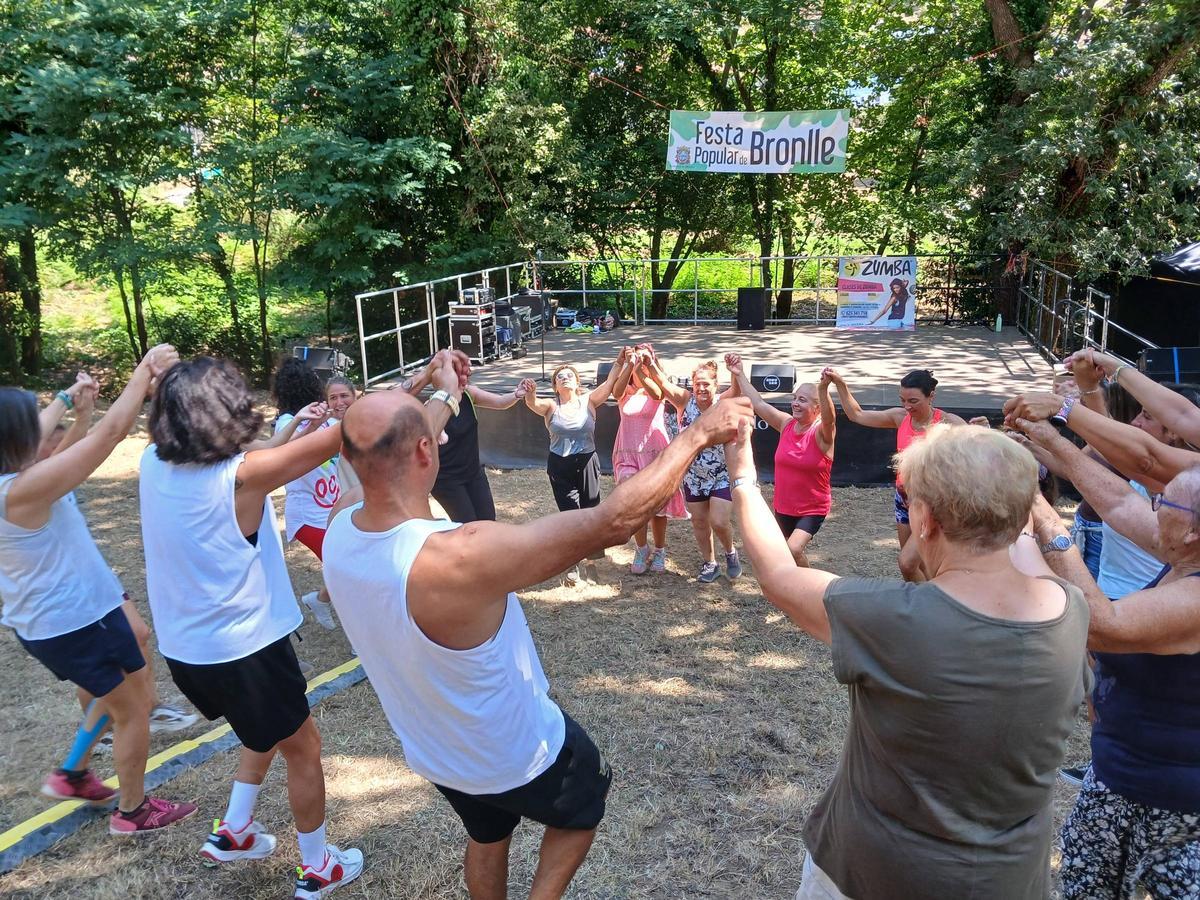 Participantes de la fiesta bailan en la carballeira de Bronlle.