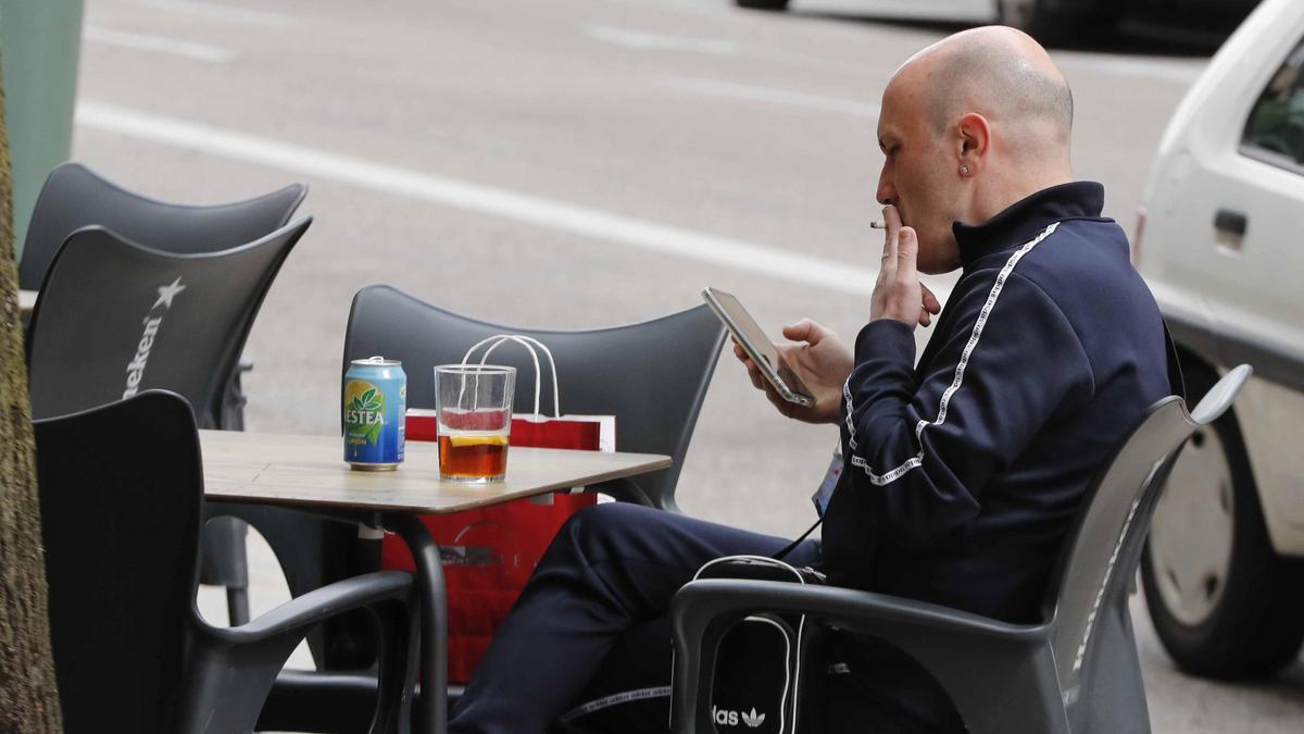 Un cliente disfruta de su consumición en una terraza de Vigo mientras fuma un cigarrillo