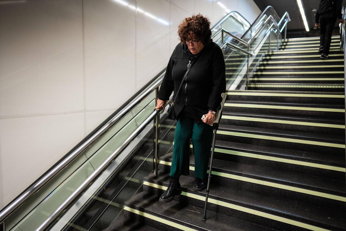 Esther Sanchís bajando con la ayuda de un muleta al andén de Rodalies en Arc de Triomf, en Barcelona.