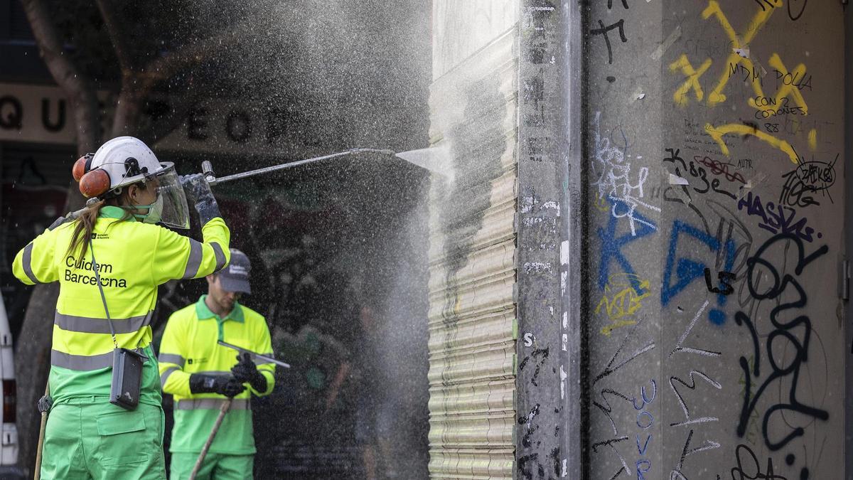 Operarios de limpieza borrando un grafiti en Barcelona.