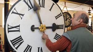 Un hombre cambia la hora a un reloj.