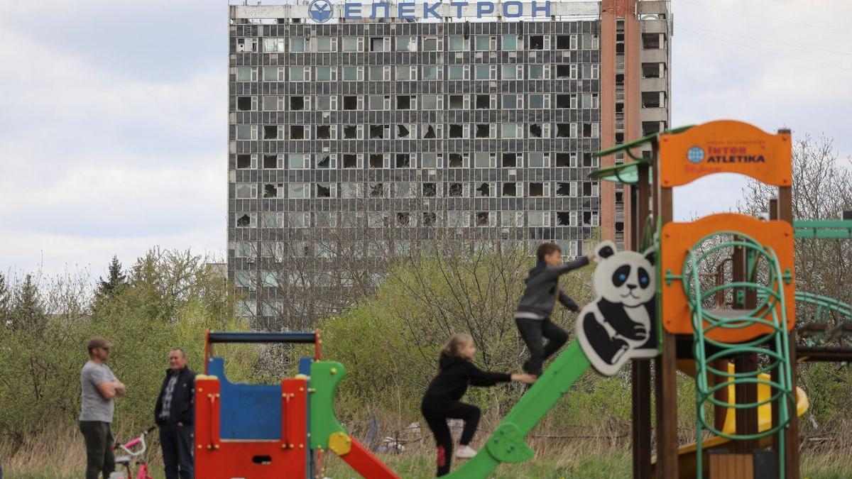 Un grupo de niños juega frente un edificio golpeado por las bombas, en Lviv.