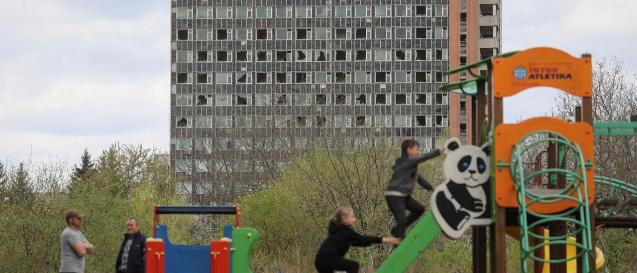 Un grupo de niños juega frente un edificio golpeado por las bombas, en Lviv.