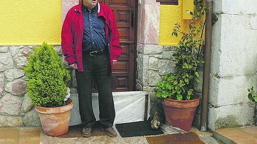 Leopoldo Rozas, ante la entrada de su casa de Balmori, que protegió con un tablón.