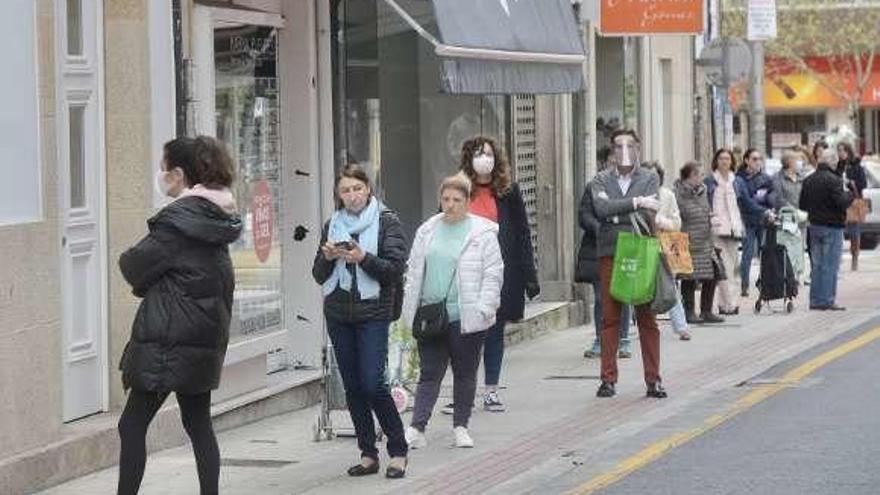 Vecinos que esperan para poder acceder a un supermercado. // R.V.