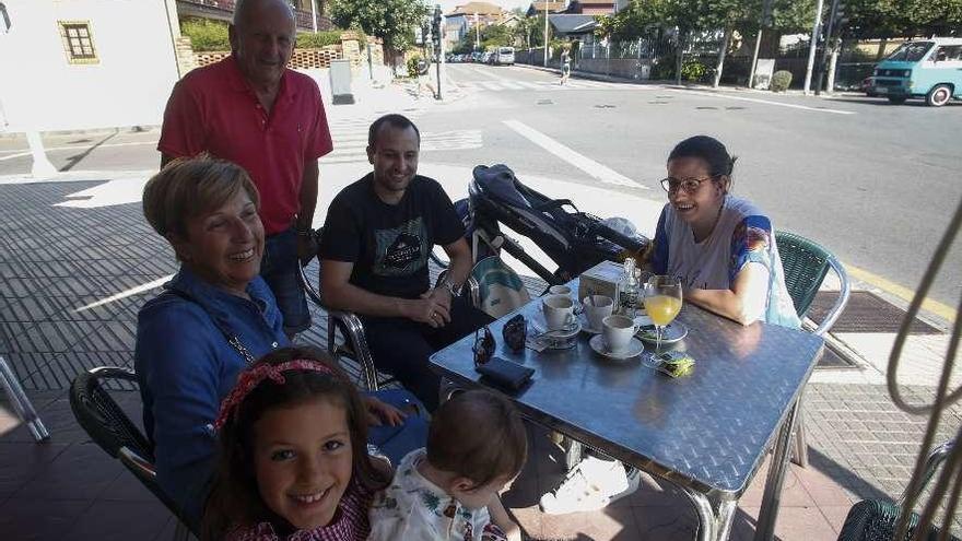 La niña Olaya Colodrón, con el bebé Ángel García en su regazo; Gala Mieres, Javier Colodrón (de pie), Adrián García y Belén García, sentados en una terraza de la calle Clarín de Salinas.