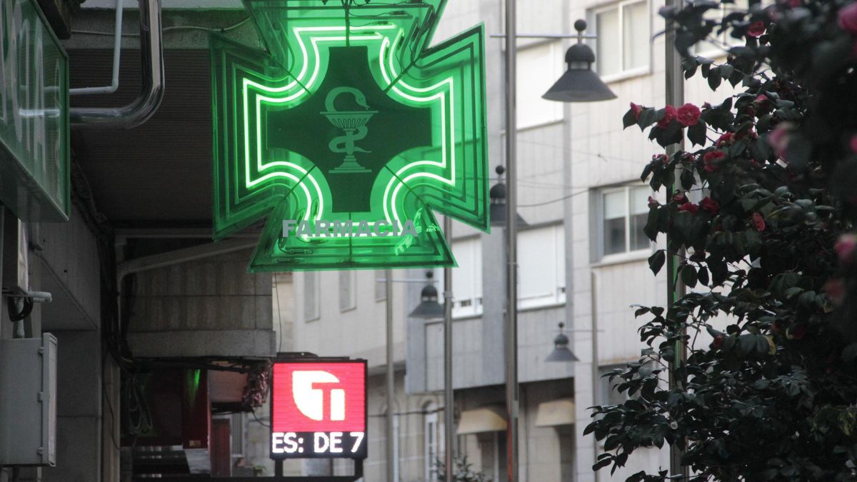 Carteles luminosos de una farmacia junto a un estanco