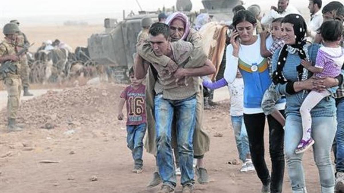 Refugiados kurdos sirios cruzan la frontera y entran en Turquía, el sábado.