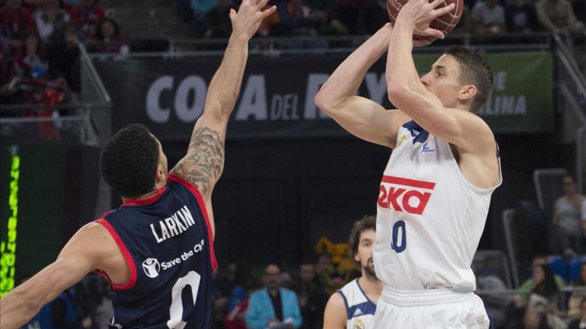 El madridista Carroll lanza a canasta en presencia del base de Baskonia, Larkin