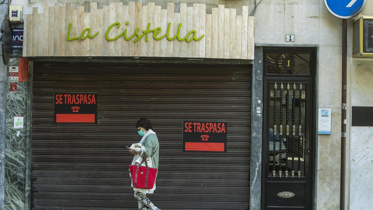 Una ciudadana pasa delante de la fachada de uno de los negocios en Elche que se ha sumado a la campaña