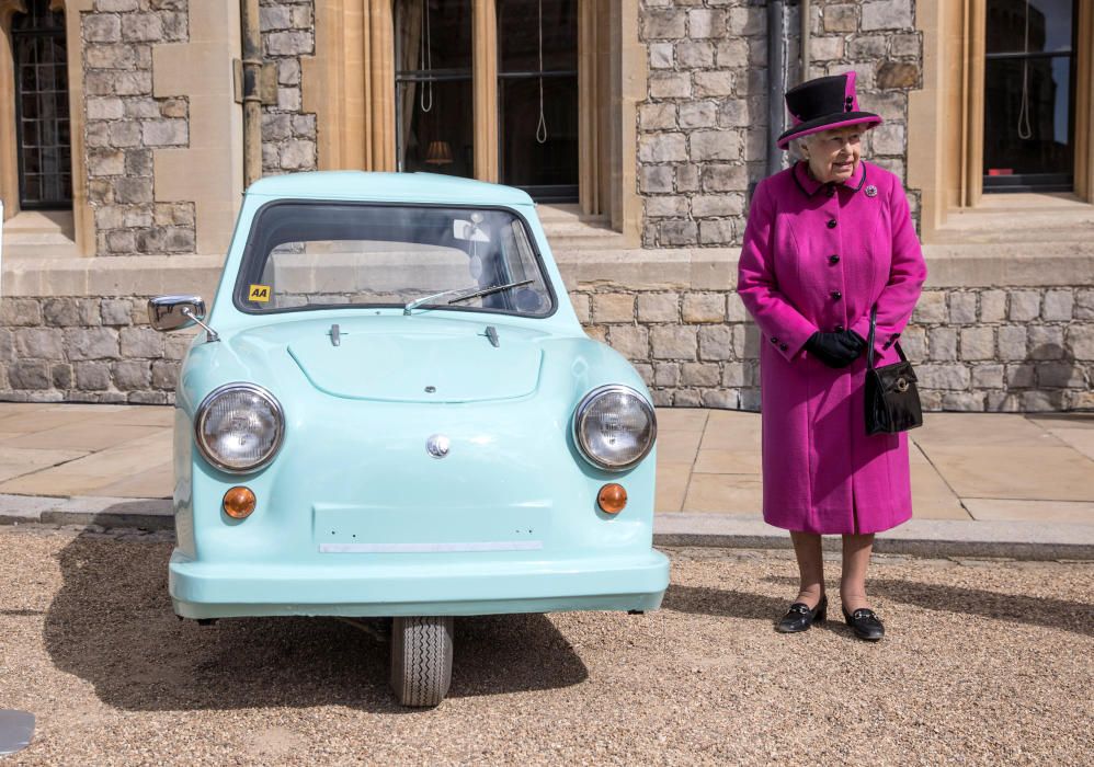 La Reina Isabel II de Inglaterra posa junto a un vehículo de bajo coste de los años 60 en el Castillo de Windsor.