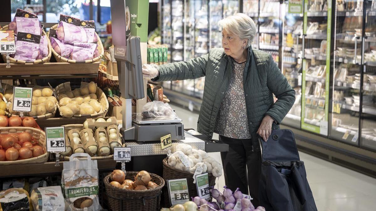 Una clienta comprueba el precio de las verduras en un supermercado.