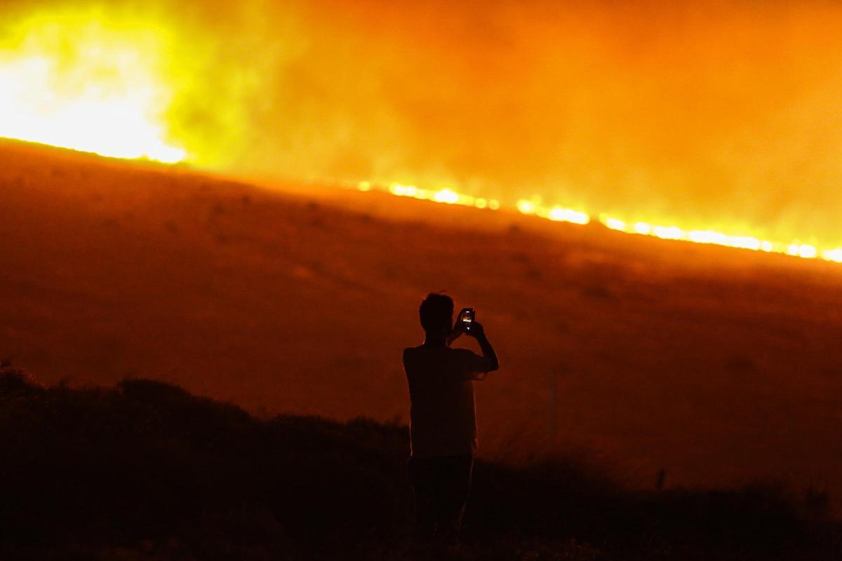 Un hombre fotografía el incendio declarado en Cesme, en la región turca de Esmira.
