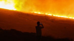 Un hombre fotografía el incendio declarado en Cesme, en la región turca de Esmira.