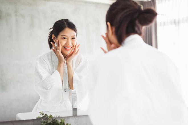 Mujer frente al espejo mientras se hace una limpieza facial