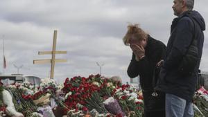 Dos vecinos del término de Krasnogorsk, en las afueras de Moscú, colocan flores en el altar improvisado de homenaje a las víctimas del ataque yihadista al Crocus City Hall.