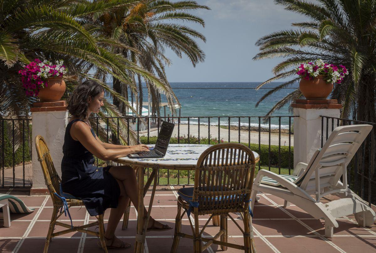 Una mujer teletrabaja desde la playa.