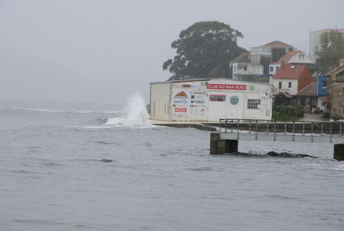 El antiguo muelle de Attilio, donde se colocarán dos bases “Coastsnap”, una en cada sentido, y el mar rompiendo contra la zona de la nave de deportes náuticos de Pescadoira. |   // GONZALO NÚÑEZ