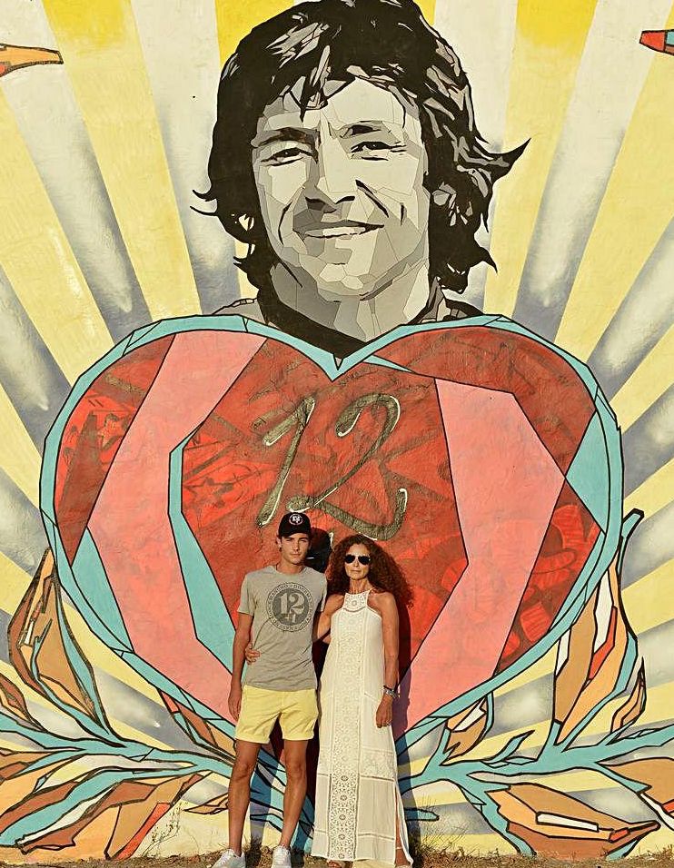 Hugo Nieto y Belinda Alonso ante el mural en memoria del fallecido piloto en el cruce de Santa Gertrudis.