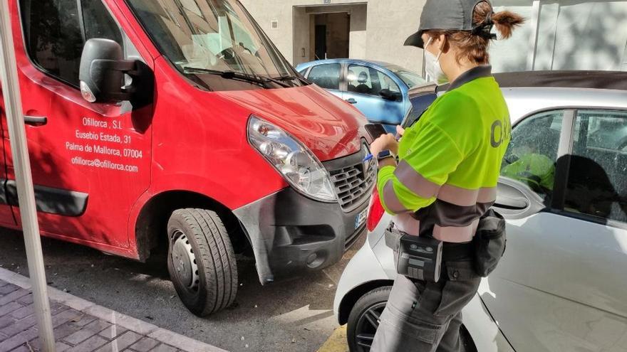 Un agente de la ORA inspecciona un vehÃ­culo aparcado en la zona de estacionamiento de pago.