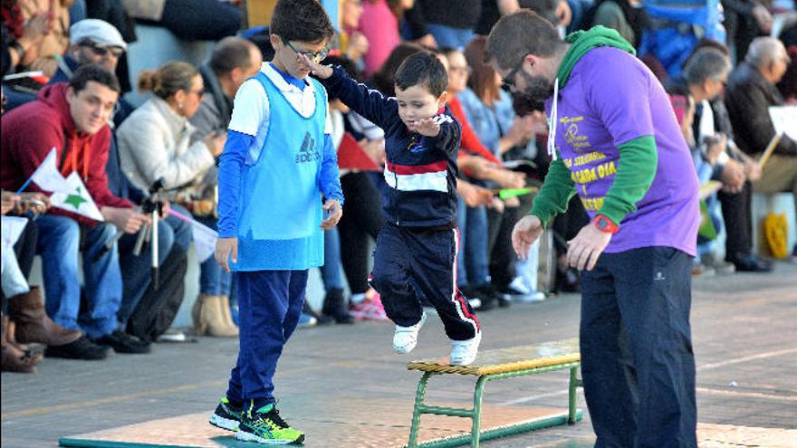 Tomás Benítez (dcha.) ayuda a uno de los alumnos de Infantil a superar un obstáculo junto a uno de los voluntarios.