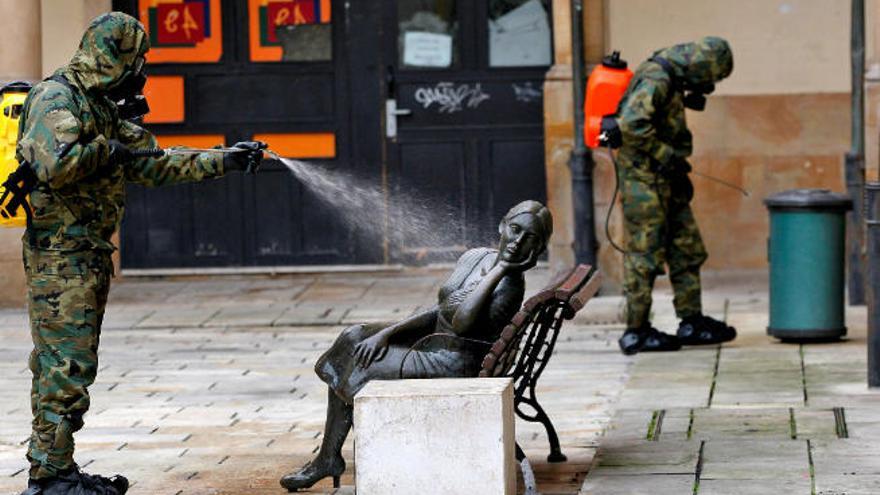 Un soldado desinfecta una escultura en una de las plazas del mercado del Fontán, en Oviedo.