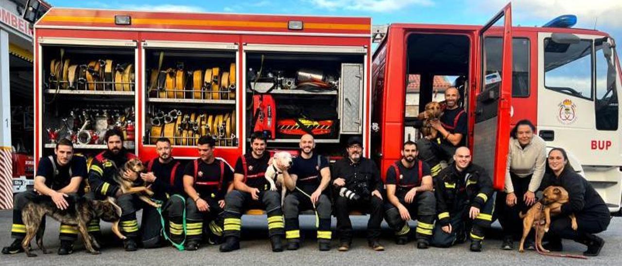 Fotografía de los bomberos con los perros, personal de Os Palleiros y el fotógrafo Miguel Vidal.