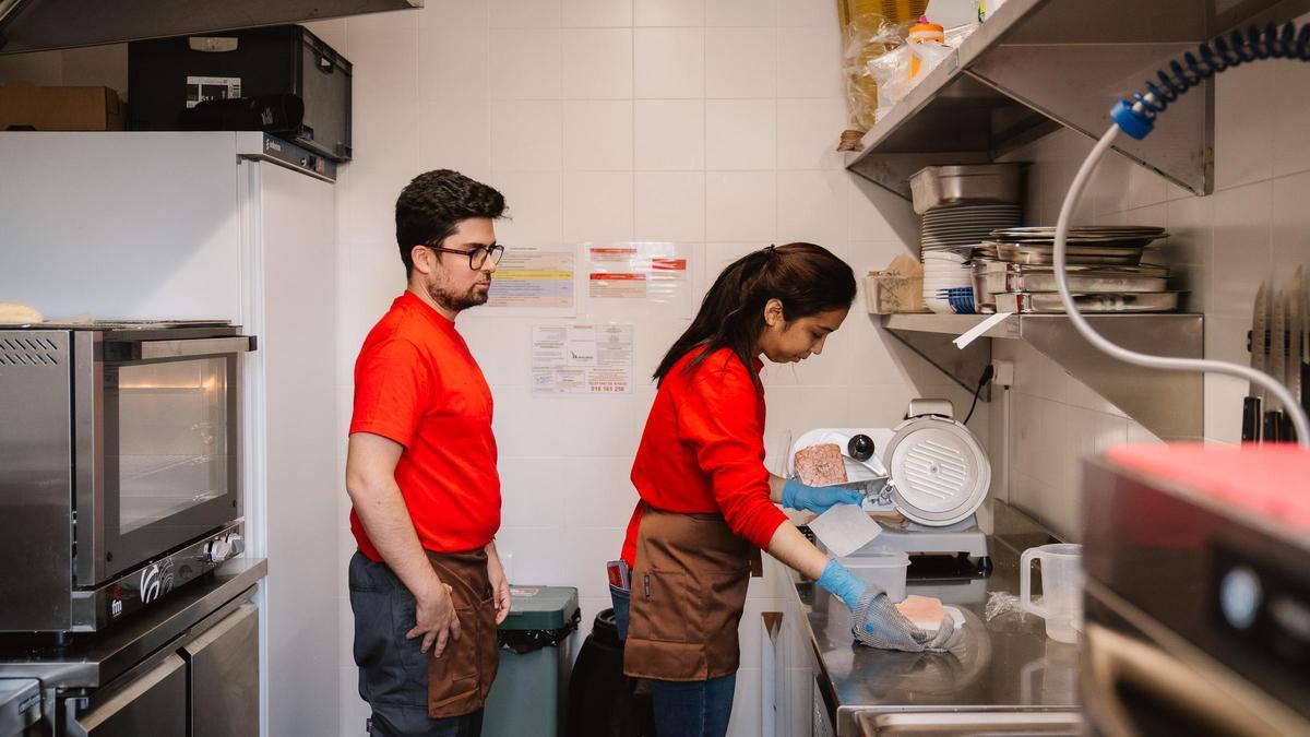 Emilio y Luz en la cocina de Envera Gastro, la primera cafetería municipal atendida por personas con discapacidad en Madrid.