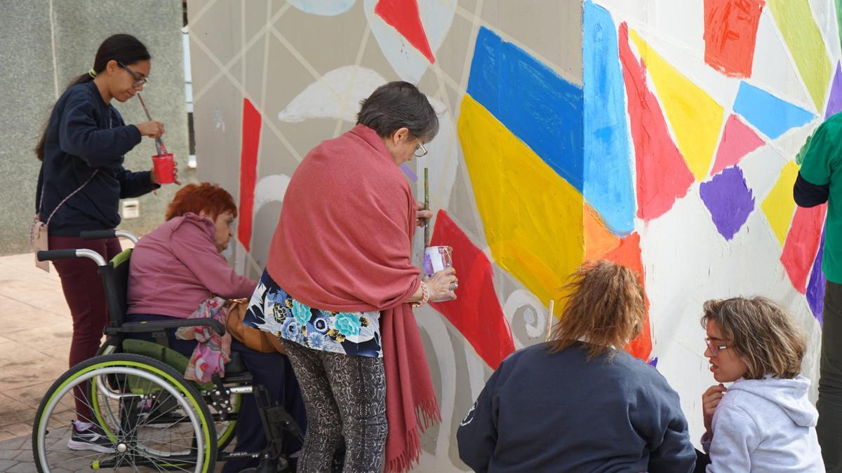 Personas usuarias de Savia Xirivella y de asociación Cotlas pintando el mural.