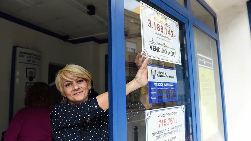 Carmen, la lotera, colocando el cartel del premio vendido.