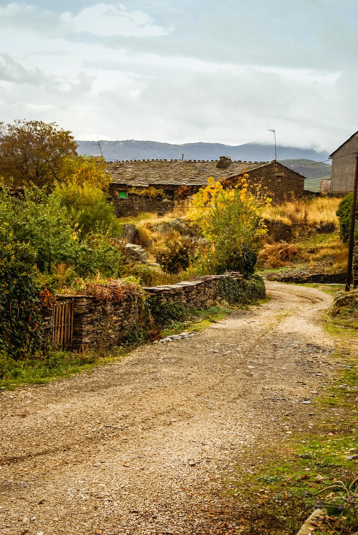 Un sendero de entrada a Majaelrayo deja entrever la arquitectura de pizarra