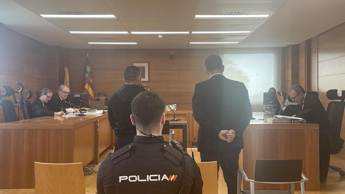 El acusado (izda.), junto al intérprete de rumano y custodiado por un agente de la Policía Nacional.