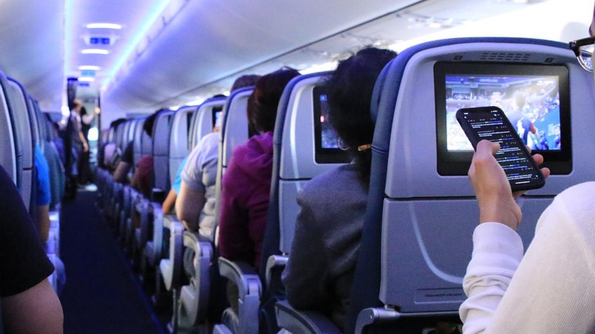 Un hombro con su móvil en un avión.