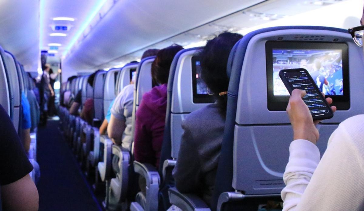 Un hombro con su móvil en un avión.