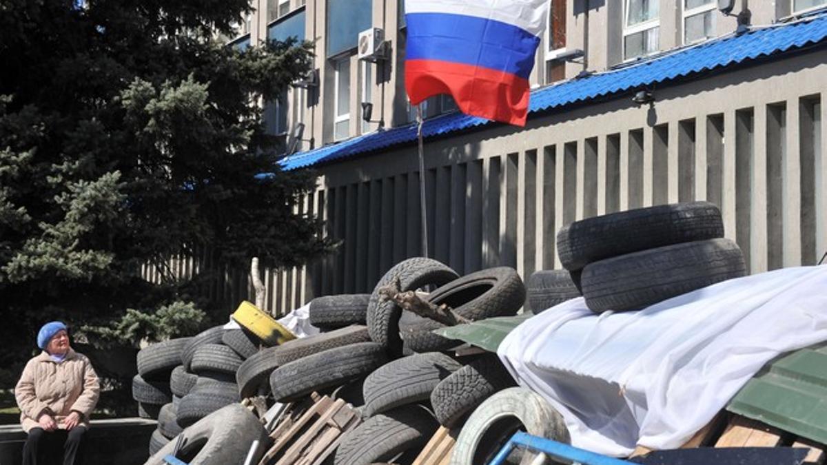 Una mujer observa la bandera rusa en una barricada que bloquea el acceso a la sede del Servicio de Seguridad de Ucrania, el martes en Lugansk.