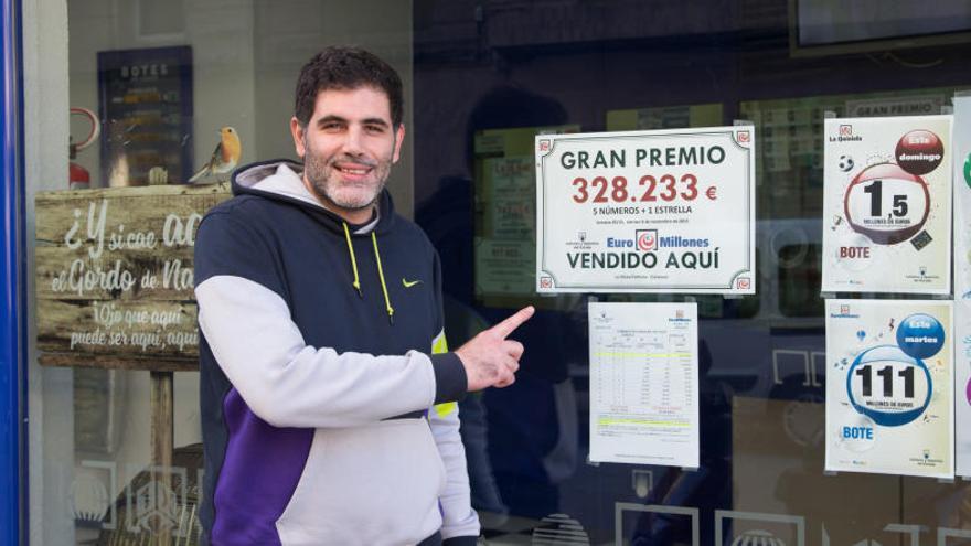 Ángel Estela señala el cartel que anuncia el premio.