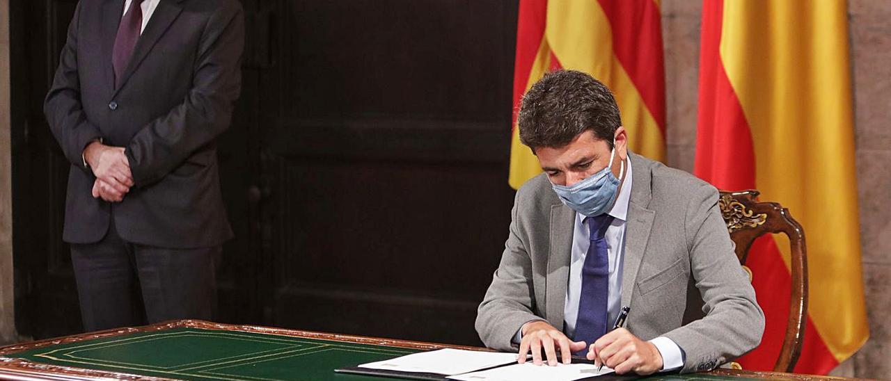 Carlos Mazón, en el Palau, firmando el programa de ayudas, en presencia de Ximo Puig.