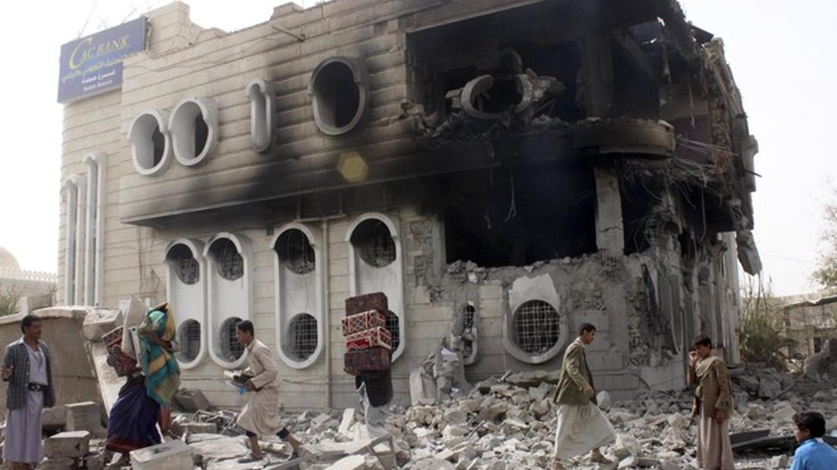 People salvage belongings from a government bank that was hit during an air strike in Yemen's northwestern city of Saada