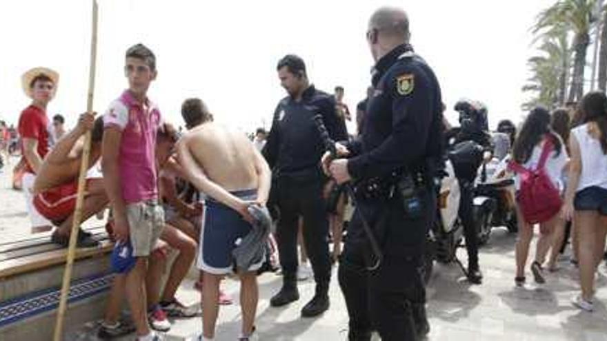 Agentes de la Policía dialogan con unos jóvenes sorprendidos bebiendo en la playa de San Juan. Sobre estas líneas un grupo de chavales conduce su carrito durante la romería.