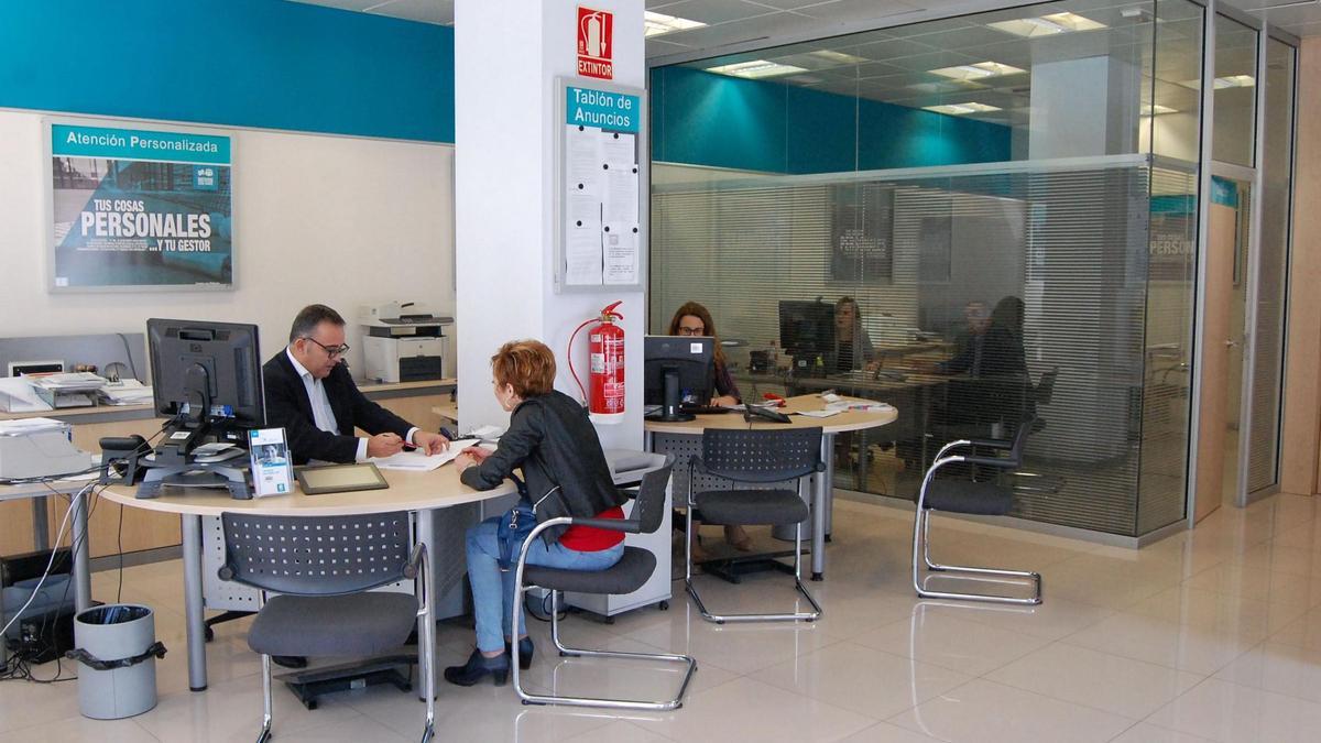 Una clienta realiza una consulta en una oficina bancaria de Castellón.