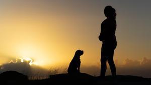 Una mujer y su perro, en el atardecer.