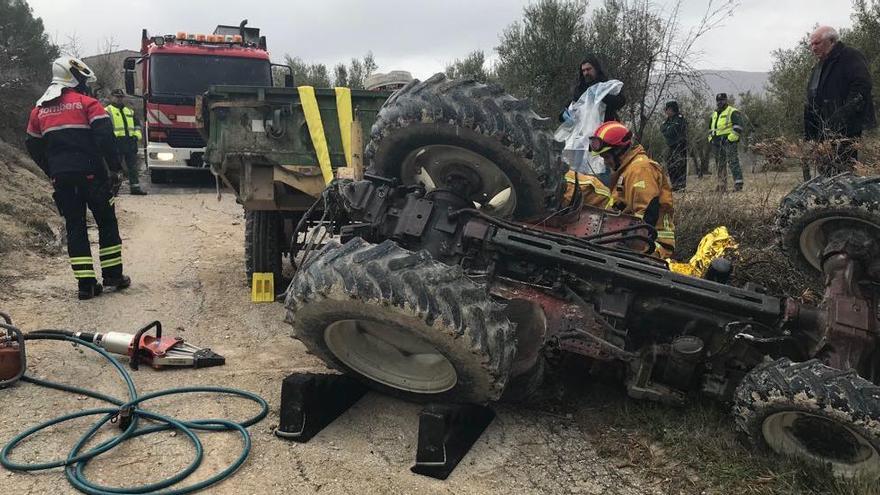 Lo bomberos rescatando el cadáver atrapado bajo el tractor