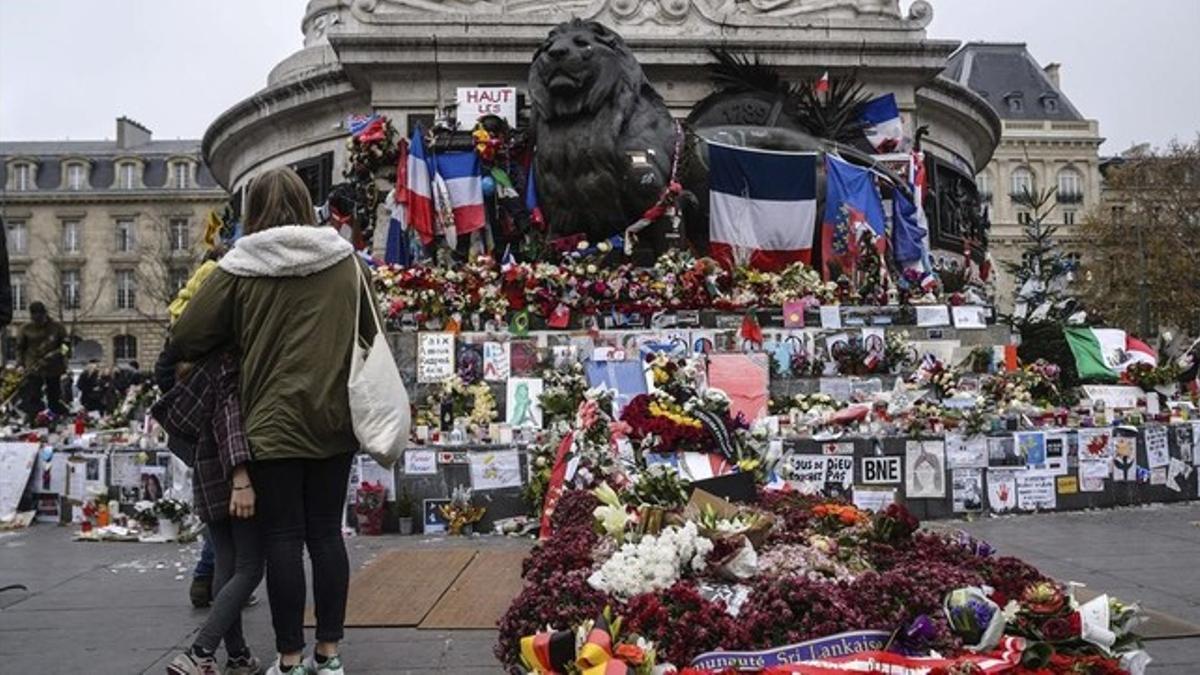 Unos jóvenes delante de uno de los homenajes del centro de París a las 130 víctimas del ataque terrorista del 13 de noviembre.