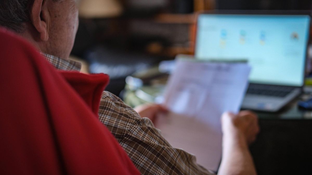 Un hombre consulta unos documentos bancarios.